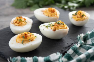 Homemade hard Boiled Deviled Eggs garnished with herbs on wooden table