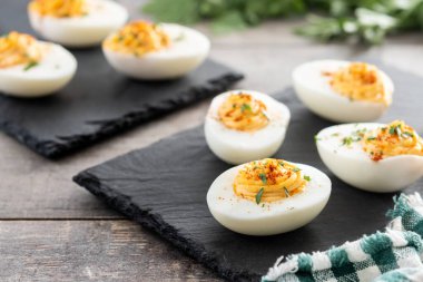 Homemade hard Boiled Deviled Eggs garnished with herbs on wooden table