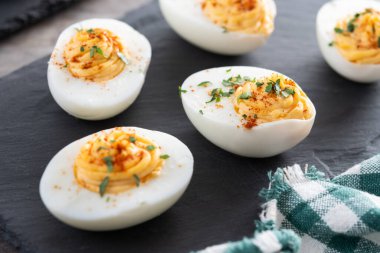 Homemade hard Boiled Deviled Eggs garnished with herbs on wooden table