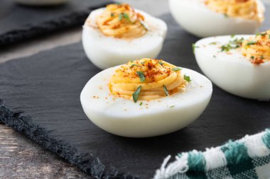 Homemade hard Boiled Deviled Eggs garnished with herbs on wooden table