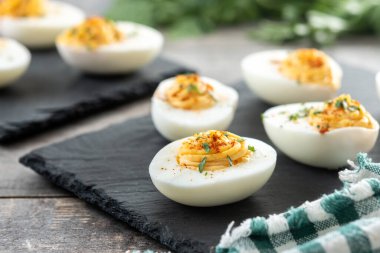 Homemade hard Boiled Deviled Eggs garnished with herbs on wooden table