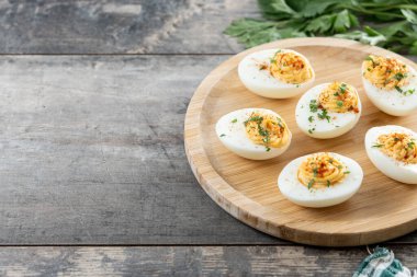 Homemade hard Boiled Deviled Eggs garnished with herbs on wooden table. Copy space