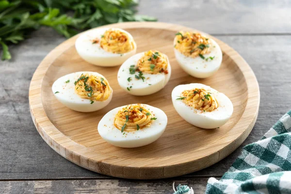 Homemade hard Boiled Deviled Eggs garnished with herbs on wooden table