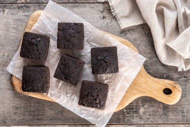 Ev yapımı çikolatalı browni. Tahta masanın üzerinde şeker tozu var.
