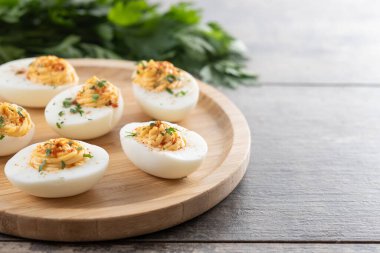 Homemade hard Boiled Deviled Eggs garnished with herbs on wooden table. Copy space