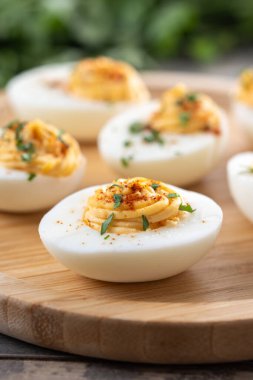 Homemade hard Boiled Deviled Eggs garnished with herbs on wooden table.
