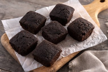 Ev yapımı çikolatalı browni. Tahta masanın üzerinde şeker tozu var.