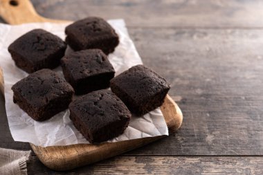 Ev yapımı çikolatalı brownie ve tahta masanın üzerinde şeker tozu. Boşluğu kopyala
