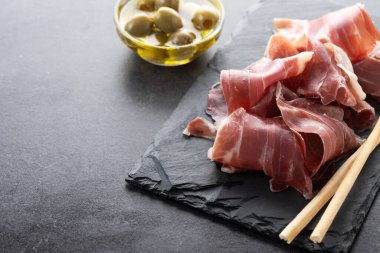 İspanyol Serrano Jambonu dilimleri siyah arkaplanda. Boşluğu kopyala