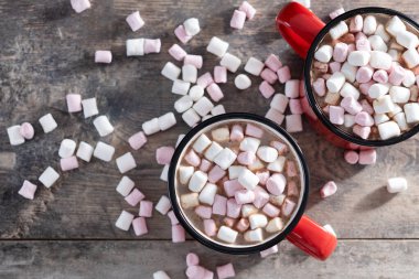 Sıcak çikolatalı içecek, marşmelovlu kırmızı bardak ve ahşap masa.