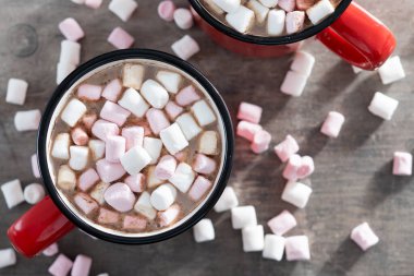 Sıcak çikolatalı içecek, marşmelovlu kırmızı bardak ve ahşap masa.