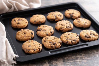 Ev yapımı çikolatalı kurabiyelerin yakın çekimi siyah bir yemek tepsisinde soğuyor..