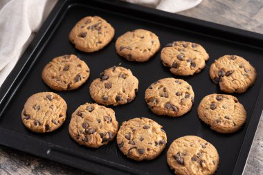 Ev yapımı çikolatalı kurabiyelerin yakın çekimi siyah bir yemek tepsisinde soğuyor..