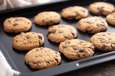 Ev yapımı çikolatalı kurabiyelerin yakın çekimi siyah bir yemek tepsisinde soğuyor..