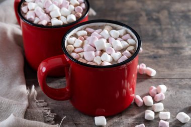  Sıcak çikolatalı içecek, marşmelovlu kırmızı bardak ve ahşap masa.