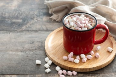 Sıcak çikolatalı içecek, kırmızı kupada marşmelov ve ahşap masa. Boşluğu kopyala