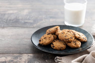 Çikolata parçalı kurabiye ve süt kırsal ahşap masada kahvaltı için.