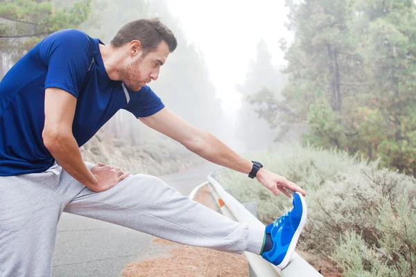 Young man exercising on the road with winter landscape background. — Stock Photo, Image