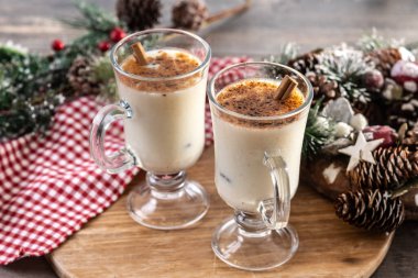 Tarçınlı eggnog ve ahşap masada Noel süsleri.