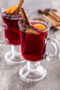 Portakallı ve tarçınlı sıcak şarap ve ahşap masada Noel süsü.