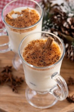 Tarçınlı eggnog ve ahşap masada Noel süsleri.