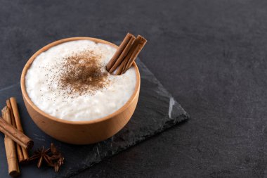 Tahta kasede sütlaç, siyah tahta zemin üzerinde.