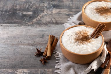 Tahta masadaki tahtadan kasede tarçınlı sütlaç. Boşluğu kopyala