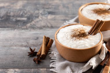 Tahta masadaki tahtadan kasede tarçınlı sütlaç. Boşluğu kopyala