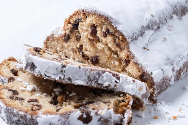 Geleneksel Noel Stollen, beyaz arka planda izole edilmiş kuru üzüm ve pudra şekerli. Kapat.