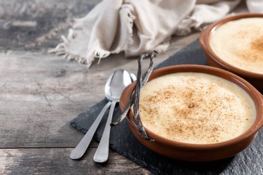 Ev yapımı kremalı İspanyol kreması ahşap masadaki bir kasede servis ediliyor. Boşluğu kopyala