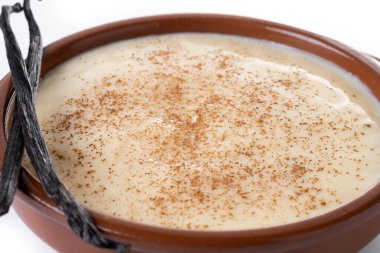 Beyaz arka planda izole edilmiş bir kasede servis edilen kremalı İspanyol muhallebisi. Kapat.