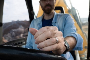 Kırsal kesimde bir kepçe yükleyici çalıştıran genç adam.