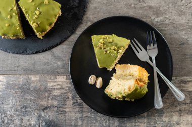 Siyah tabakta servis edilen bir dilim şam fıstıklı kek.