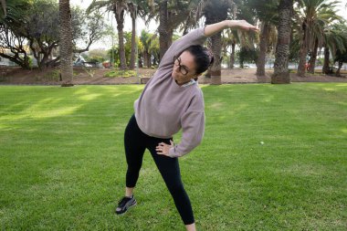 Parkta yan esneme egzersizi yapan bir kadın.