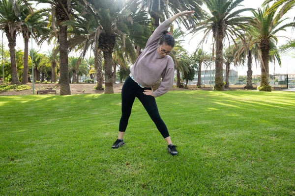 Parkta yan esneme egzersizi yapan bir kadın.