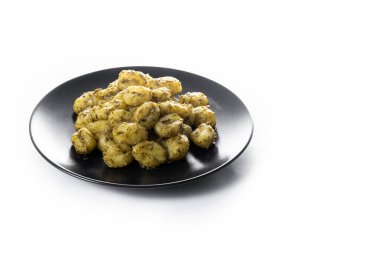 Beyaz arka planda izole edilmiş siyah tabakta servis edilen pesto soslu Gnocchi. Boşluğu kopyala