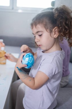 Evde Paskalya yumurtalarını süsleyen iki kız kardeş.