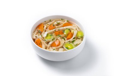 Beyaz arka planda izole edilmiş taze ev yapımı tavuk çorbası, doğranmış tavuk, havuç ve kereviz ile servis edilir.