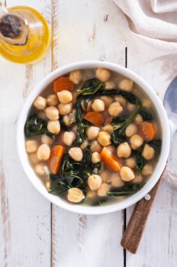 Tahta masadaki havuçlu nohut ve ıspanak çorbası.