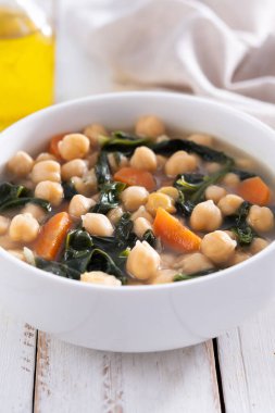 Tahta masadaki havuçlu nohut ve ıspanak çorbası.
