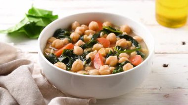 Nohut ve beyaz tahta masada havuçlu ıspanak çorbası.