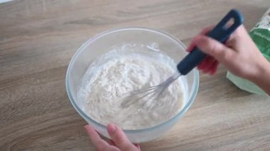 Ev yapımı ekmek hamuru yapmak için unla suyu karıştırıyorum.