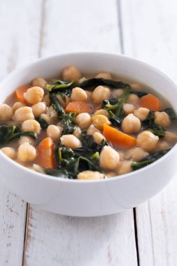 Tahta masadaki havuçlu nohut ve ıspanak çorbası.