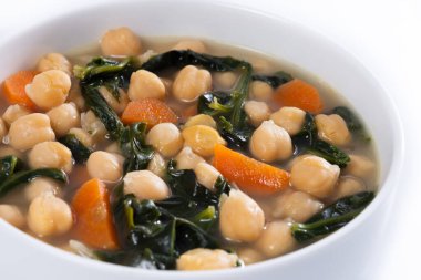 Beyaz arka planda izole edilmiş havuçlu nohut ve ıspanak çorbası. Kapat.