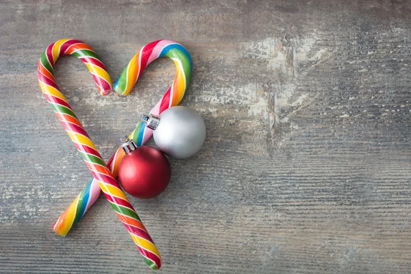 Candy bastões em forma de coração e bolas de Natal no fundo de madeira — Fotografia de Stock