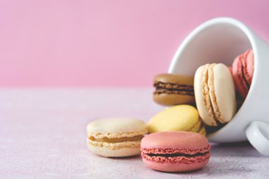 Macarons beyaz Kupası ve pembe bir arka plan
