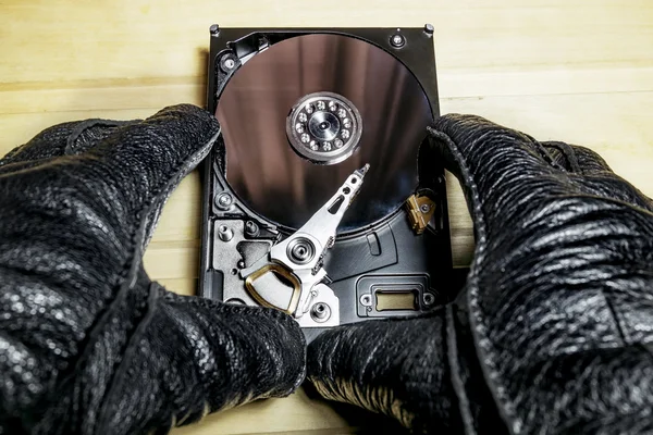 The hard drive from the computer in the hands  on a wooden surfa — Stock Photo, Image