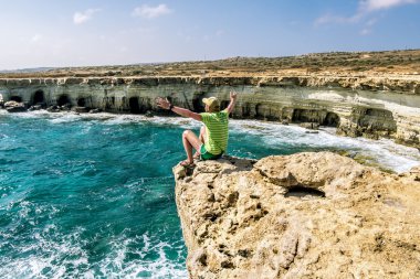 Bir çıkıntı Cape Greco adlı deniz kaya üzerinde bir adam oturuyor. Cypr