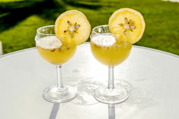 Glasses with juice and slices of lemon are on the table in sunli — Stock Photo, Image