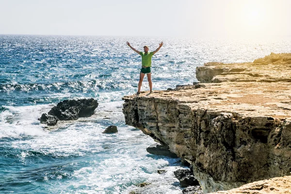 The man is throwing up his hands on the ledge of the cliff above — Stock Photo, Image